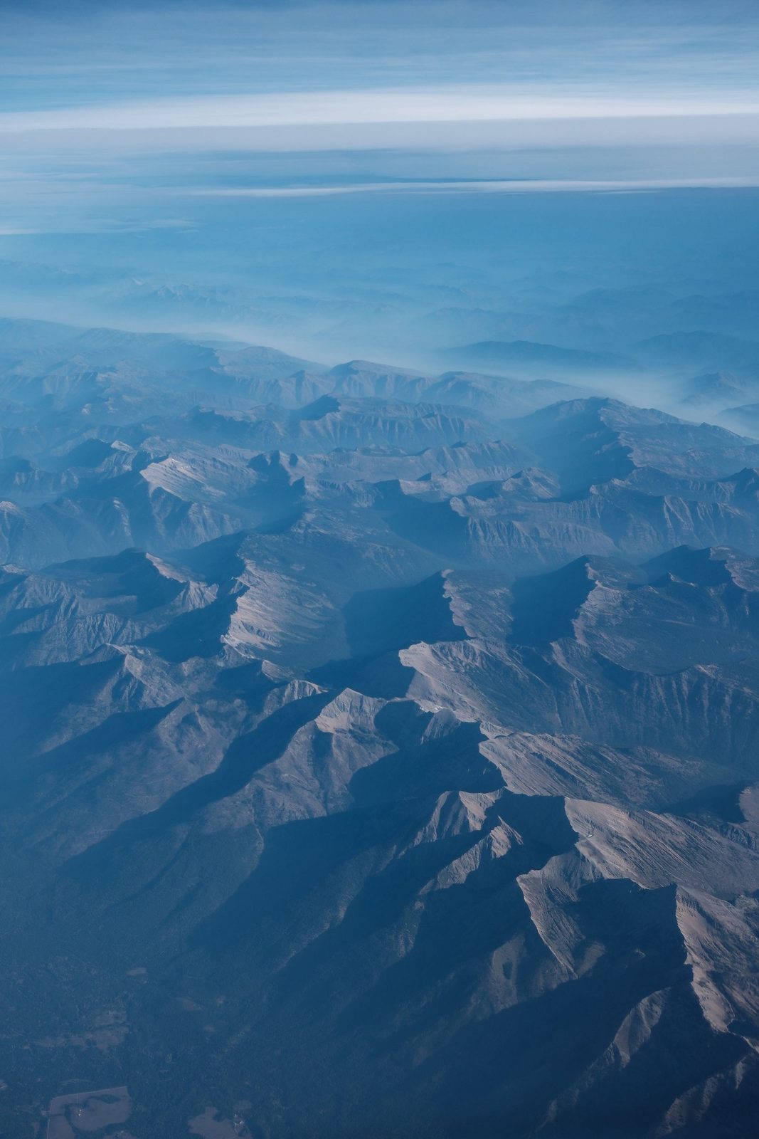 Mountain ranges fading into blue haze, seen from a plane window