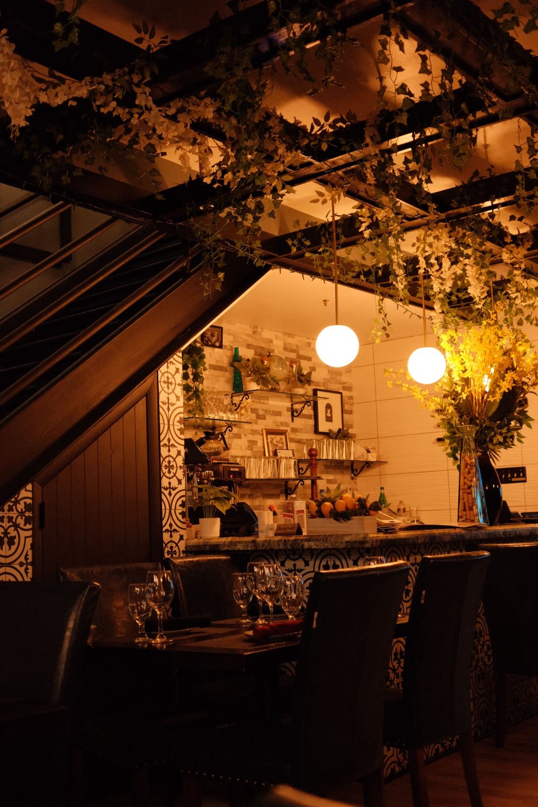 A dim restaurant draped in ivy, lit by warm globe lights