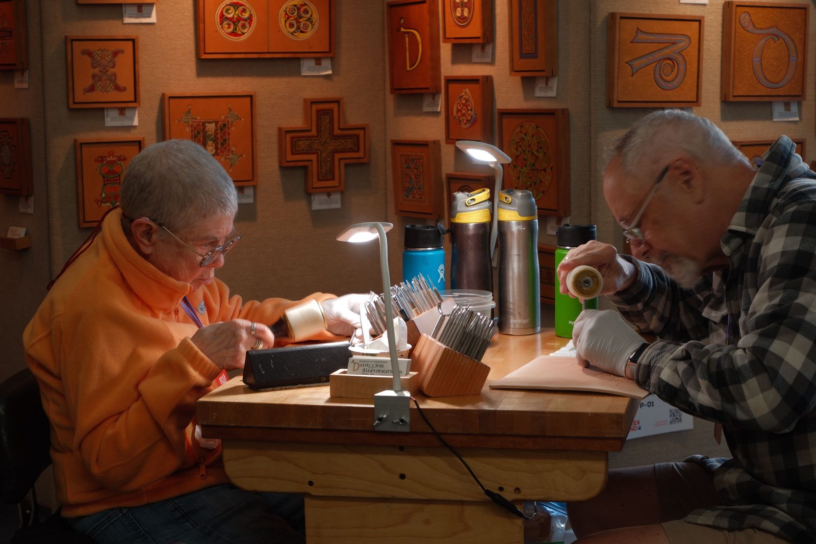 Two artisans bent over fine leatherwork at a workbench