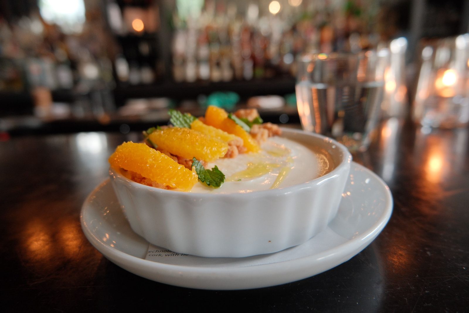 Panna cotta topped with orange segments and mint at a bar