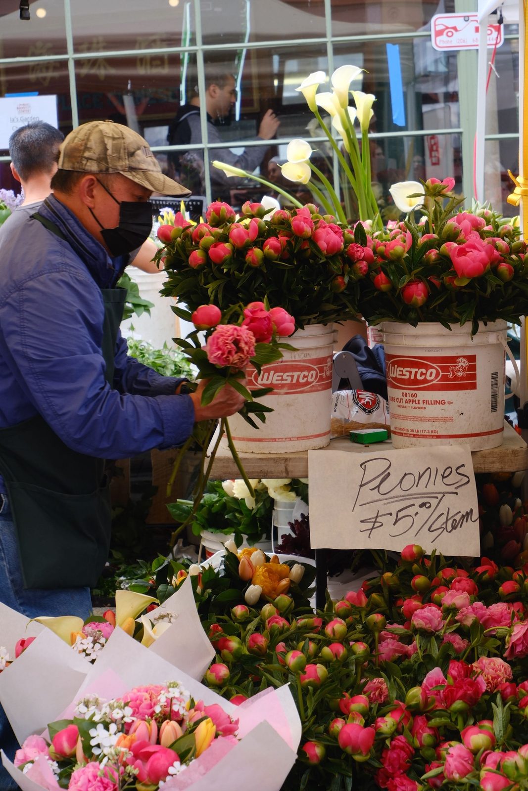A vendor arranging peonies at the Pike Place flower market
