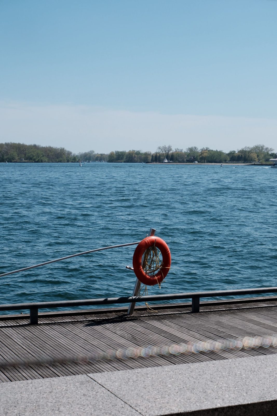 An orange life ring on a boardwalk railing above blue water