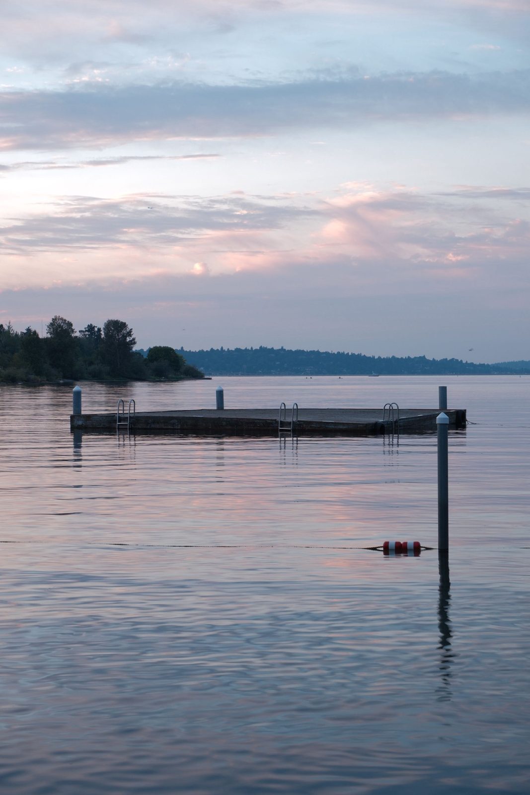 A floating dock on a still lake at dusk, sky mirrored in the water