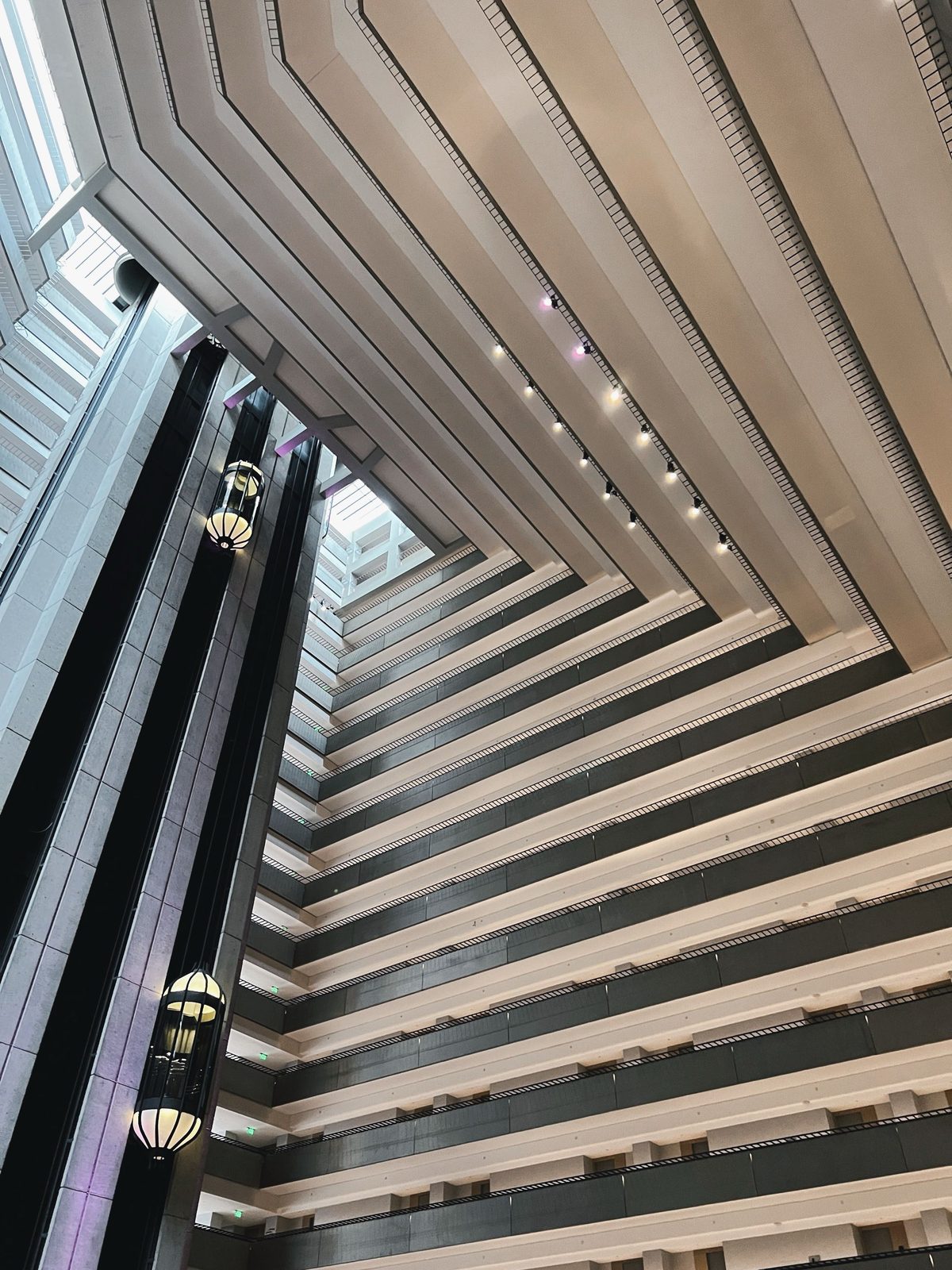 A towering hotel atrium with glass elevators and rows of balconies