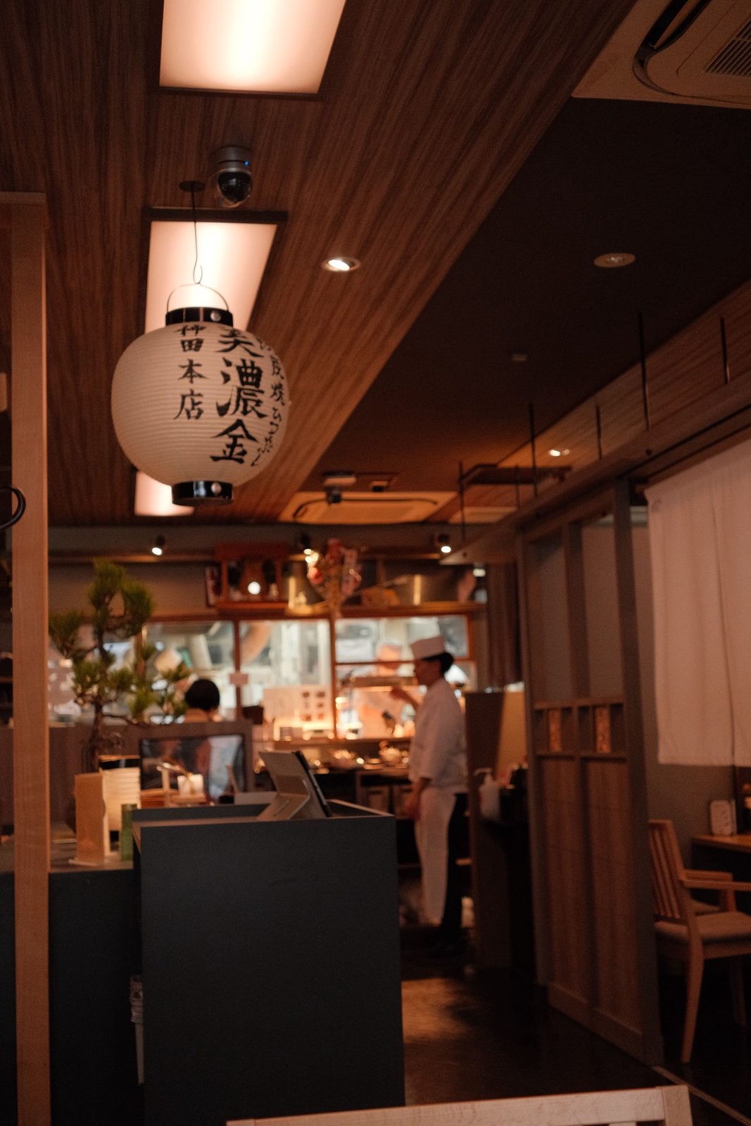Warm interior of a Japanese restaurant, paper lantern in the foreground