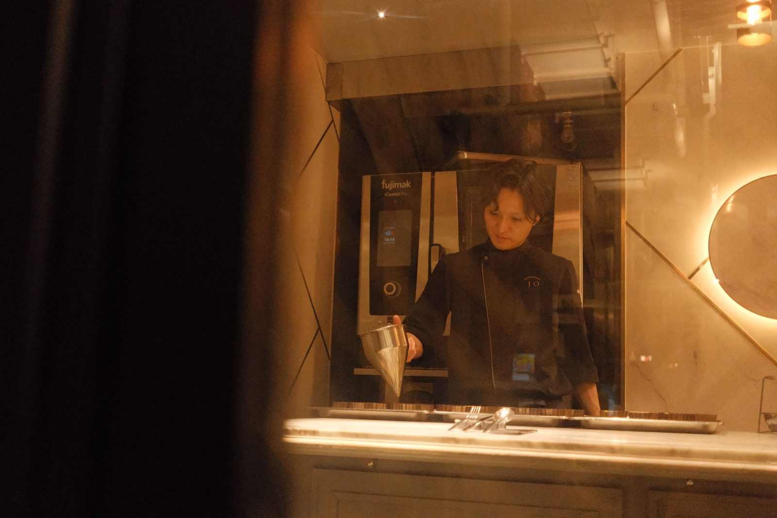 A chef at work, framed through a warm kitchen window