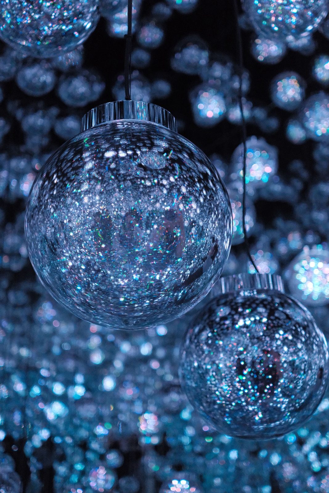 Blue glitter glass ornament balls suspended in darkness