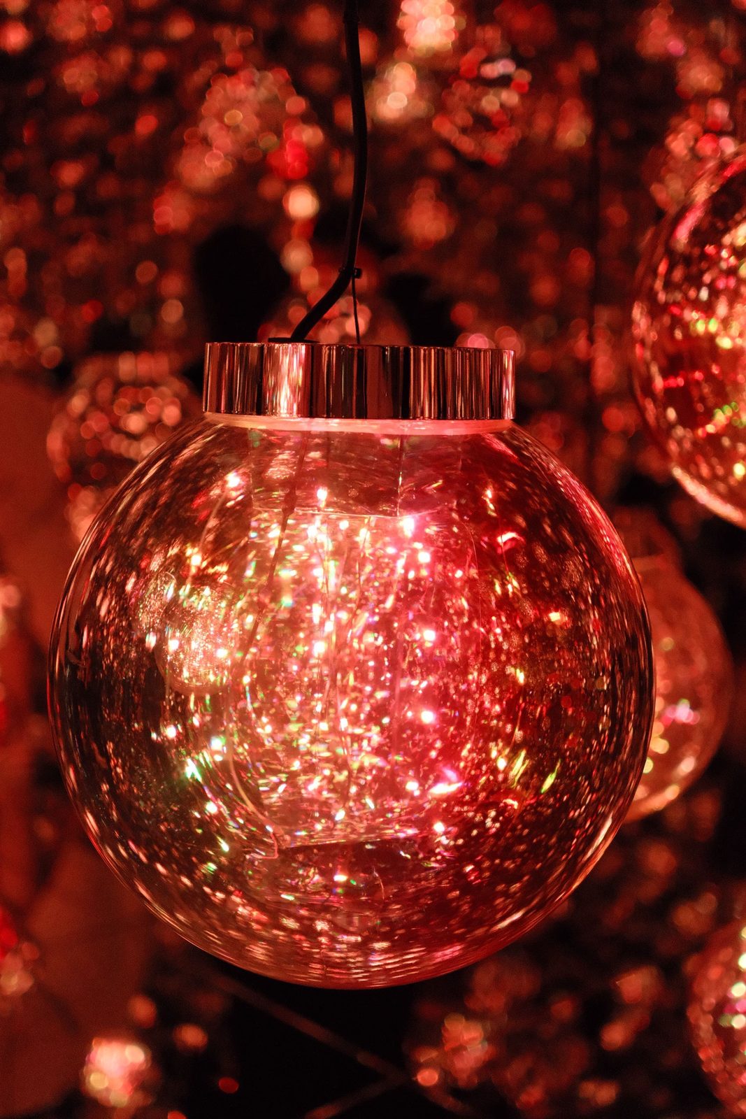 A single red glitter glass ornament ball glowing in the dark