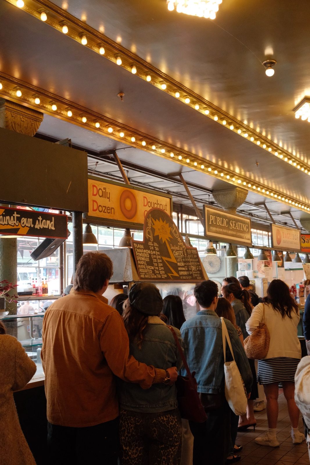 The Daily Dozen doughnut stand under warm marquee lights at Pike Place Market