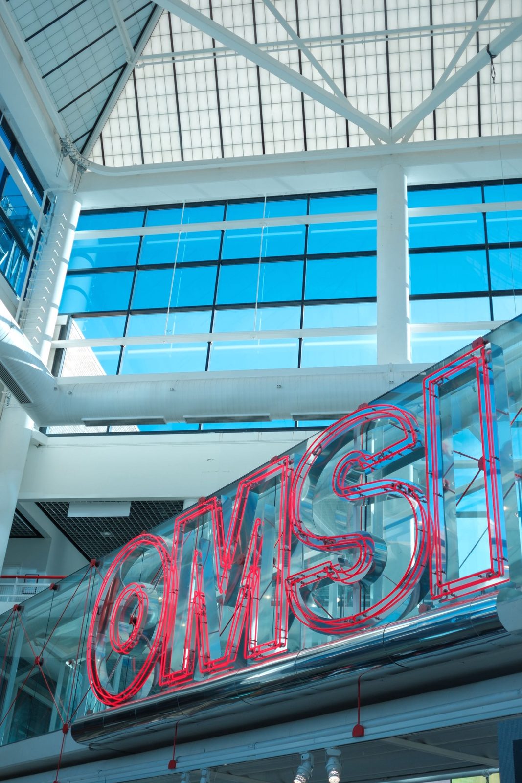 The OMSI neon sign inside a bright museum atrium