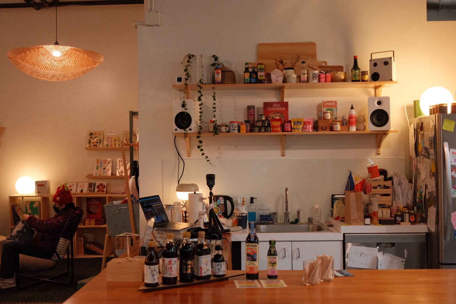 A cozy cafe interior with shelves of pantry goods and warm lighting