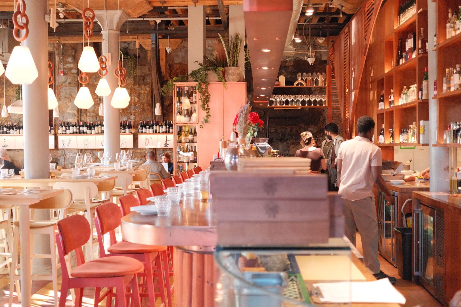 An airy restaurant with pink stools and a long bar