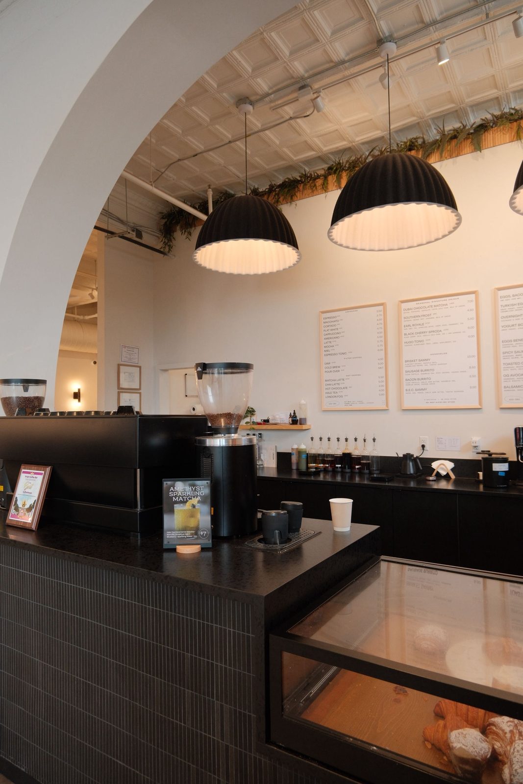 A modern coffee bar with sculptural pendant lights and a chalk menu