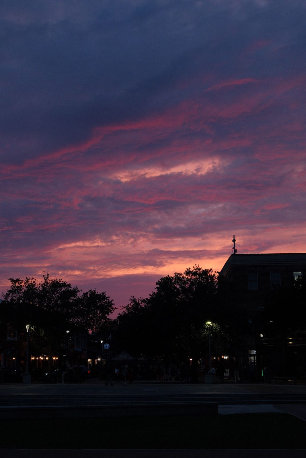 A pink and purple sunset over a town square