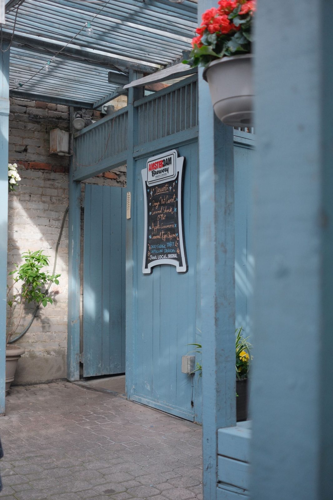 A blue-painted courtyard doorway with a chalkboard menu and potted flowers