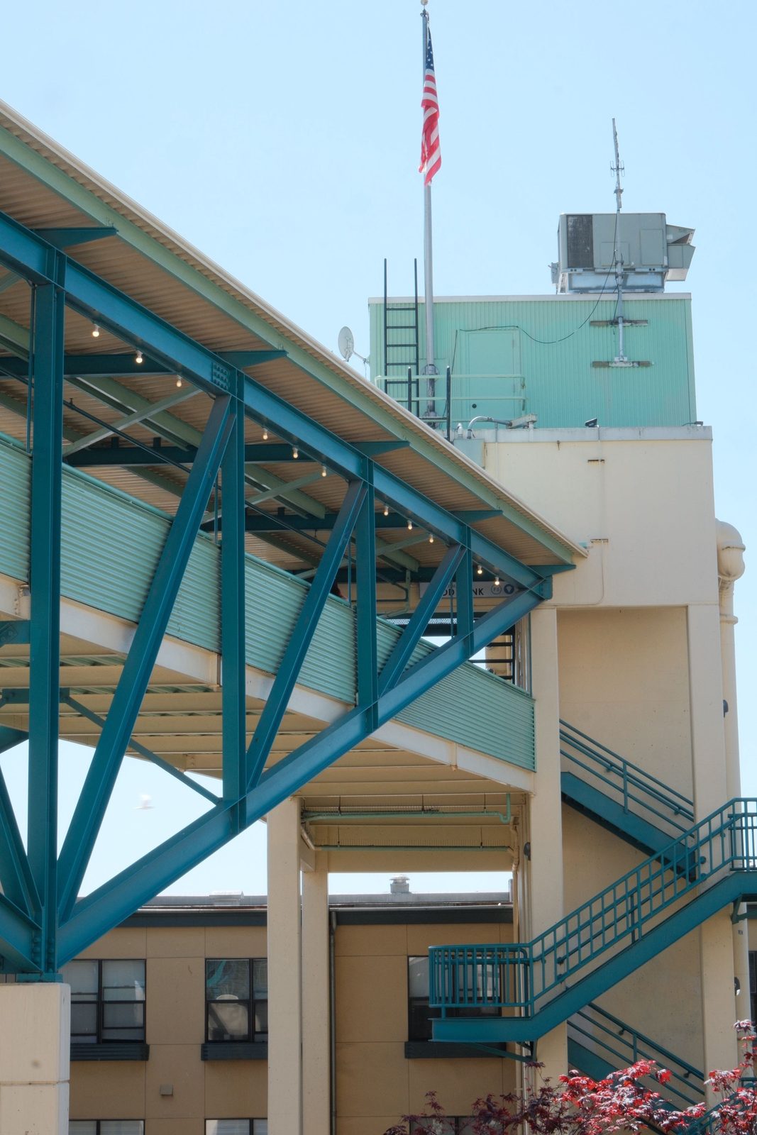 A teal steel pedestrian bridge against a clear sky