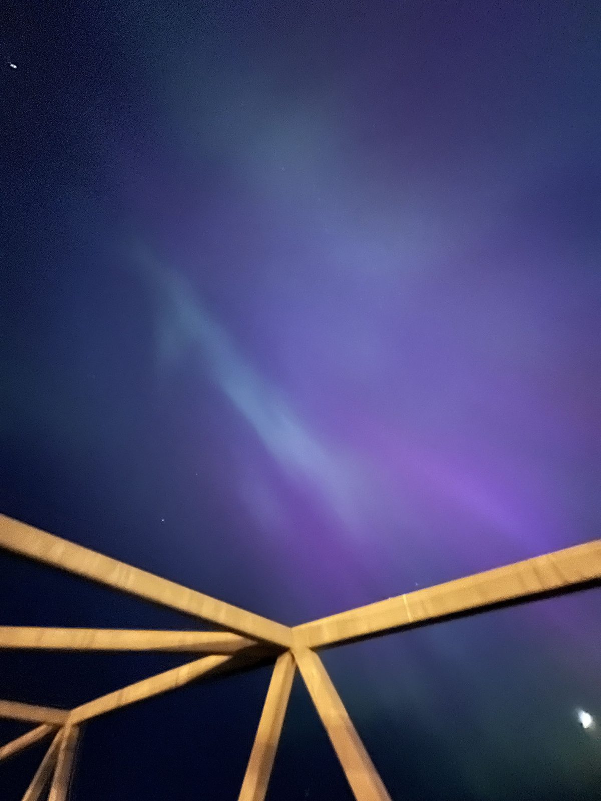 Faint purple northern lights over a wooden structure