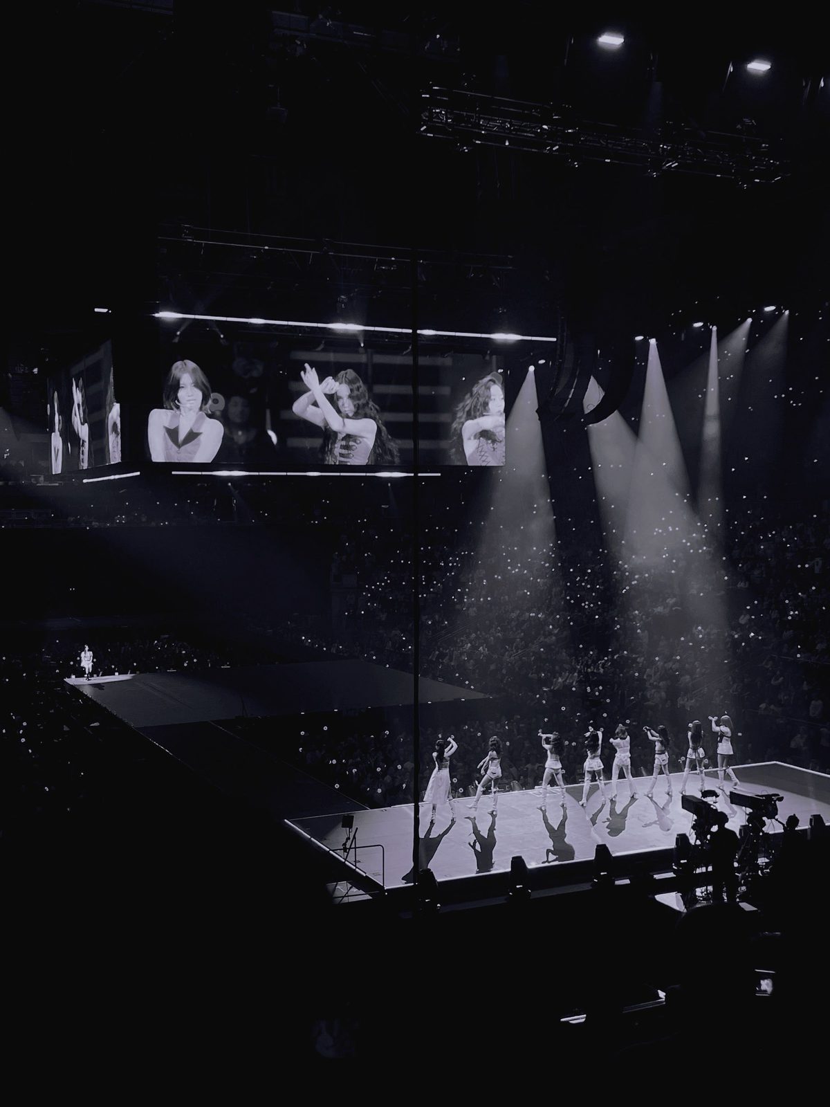 A concert in black and white, dancers lit by spotlights