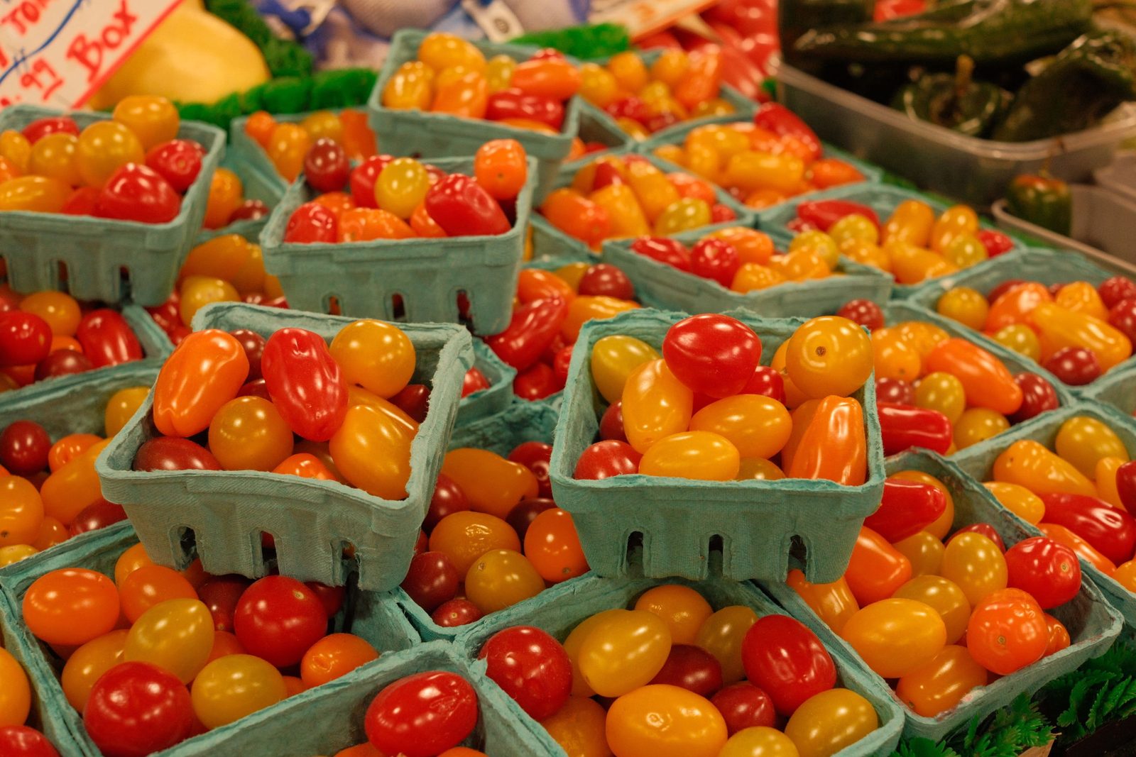 Cartons of red and yellow cherry tomatoes stacked at a market stall