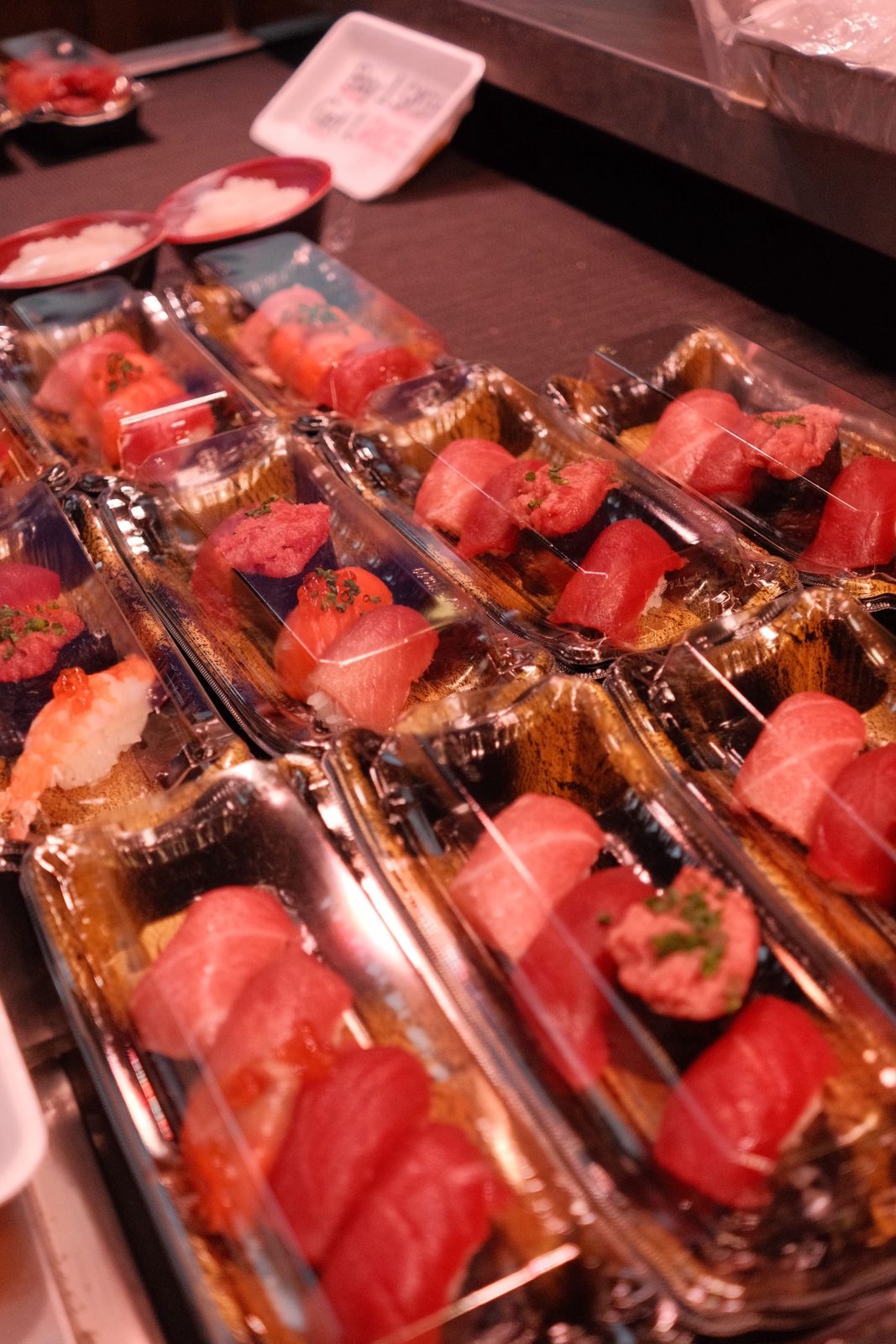 Trays of fresh tuna nigiri lined up at a sushi counter