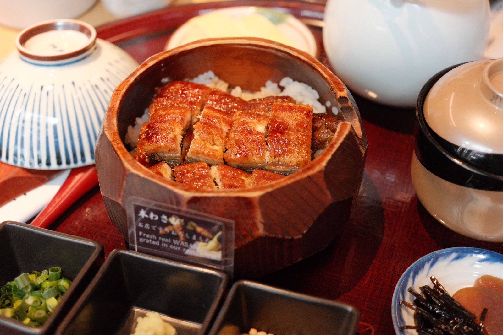 Grilled unagi over rice in a wooden bowl, part of a Japanese set meal