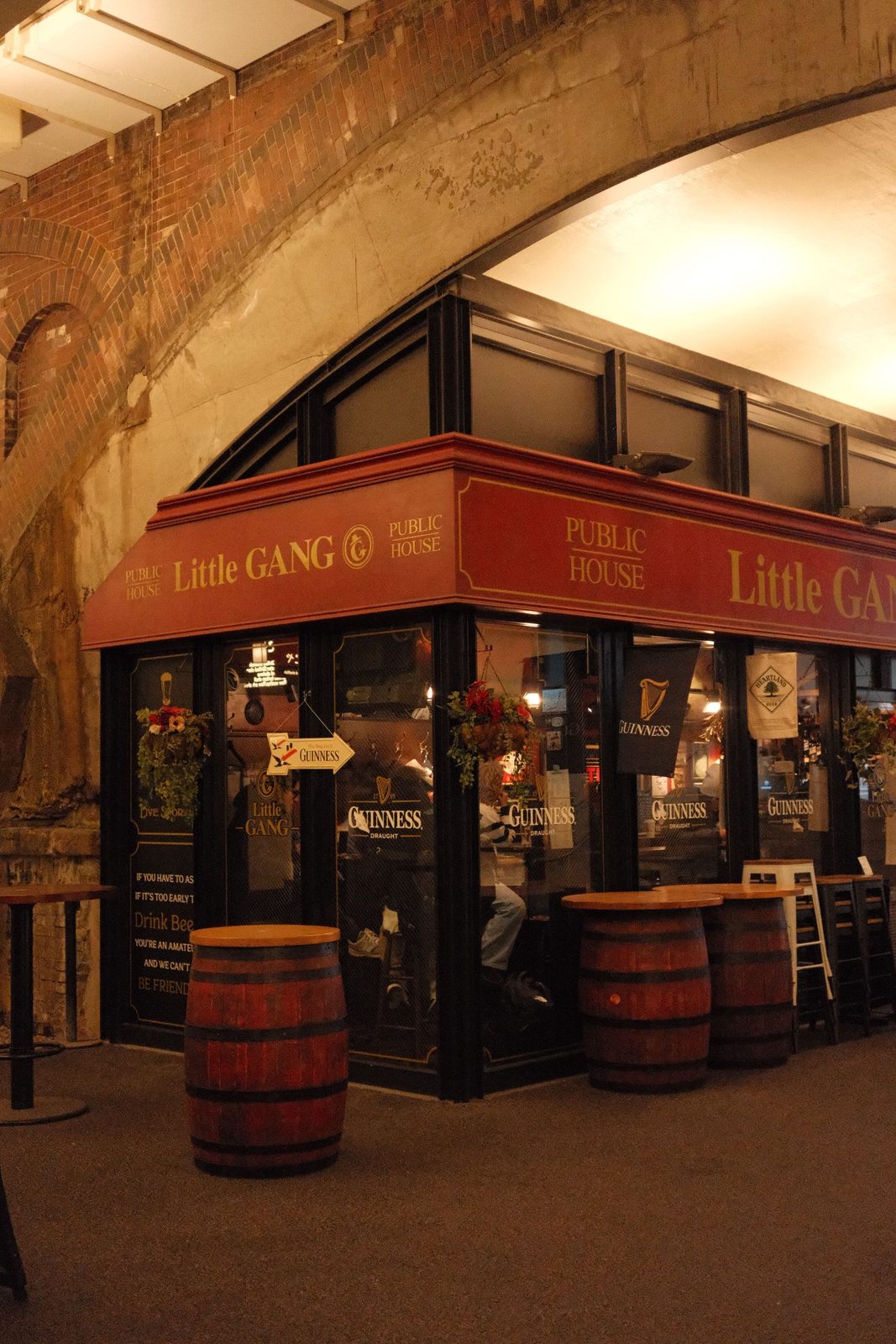 The Little Gang Public House tucked under brick arches, with barrel tables