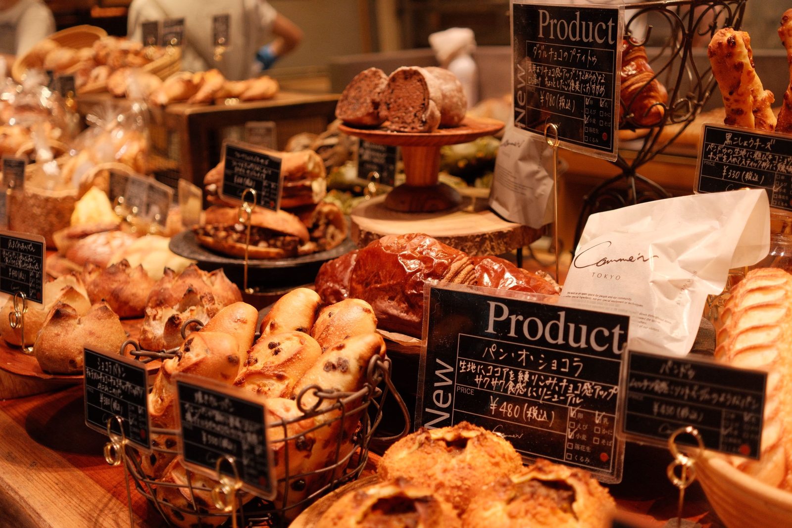 A bakery case crowded with breads and pastries and handwritten signs