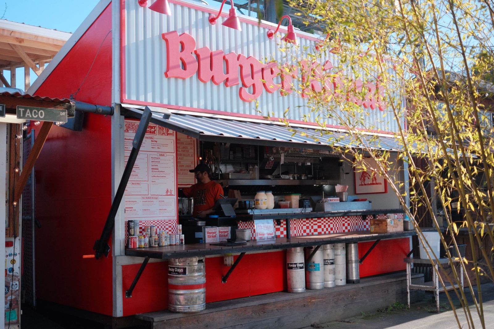 A bright red Burger food stand with the cook at the window