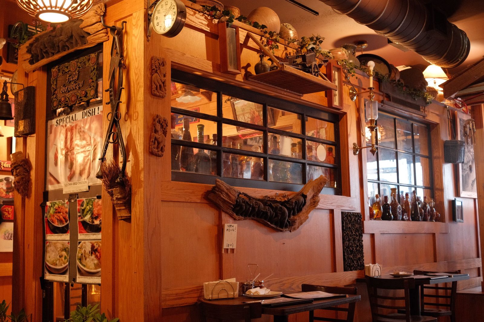 A cozy, wood-panelled restaurant interior lined with bottles and posters